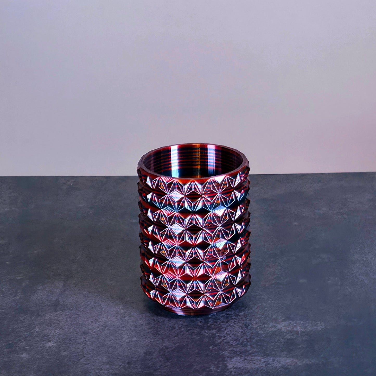 Red Cup with Black Stripes and Geometric Texture against Stone Background