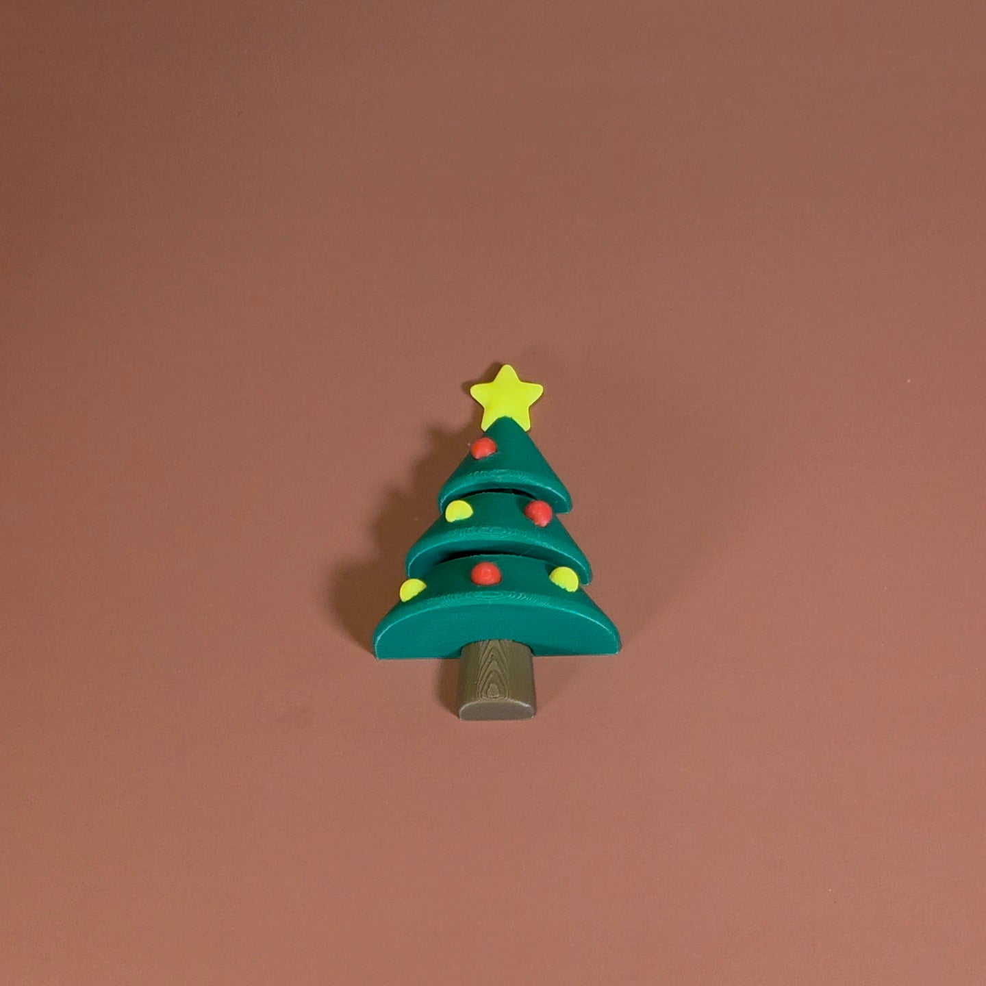 Toy Christmas tree with a star on top against a brown background