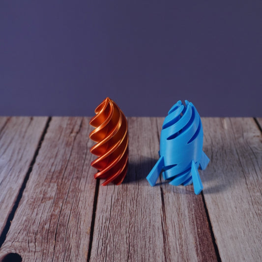 Blue and orange plastic rocket fidget items on a wooden surface with a purple background