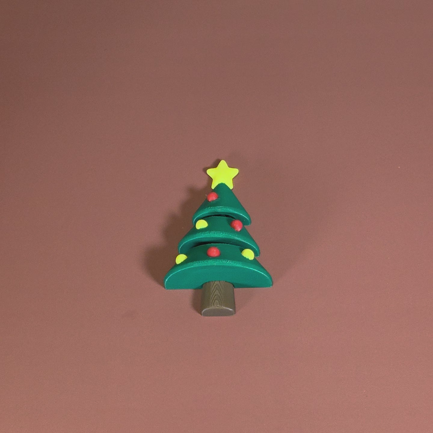 Toy Christmas tree with a star on top against a brown background