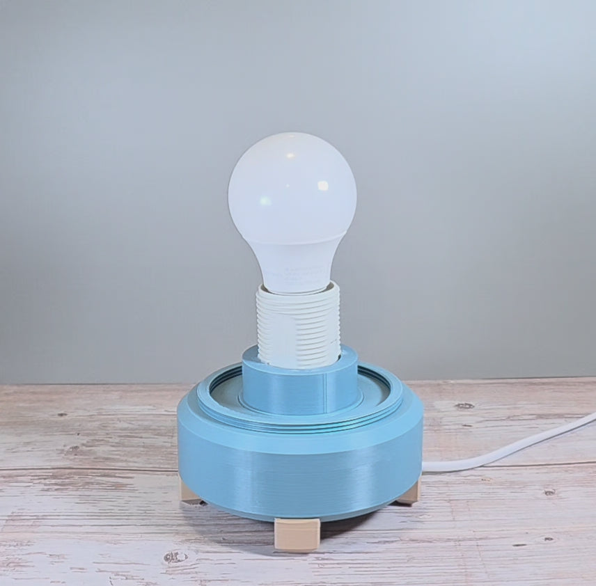 Gray Blue Lamp Base with White Lamp Shade containing Geometric Texture against Wooden and Light Gray Background